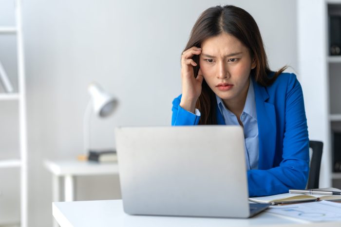 Tired Asian businesswoman, headache, stressed, sleepy and bored from sitting at a table for a long time and have office syndrome.